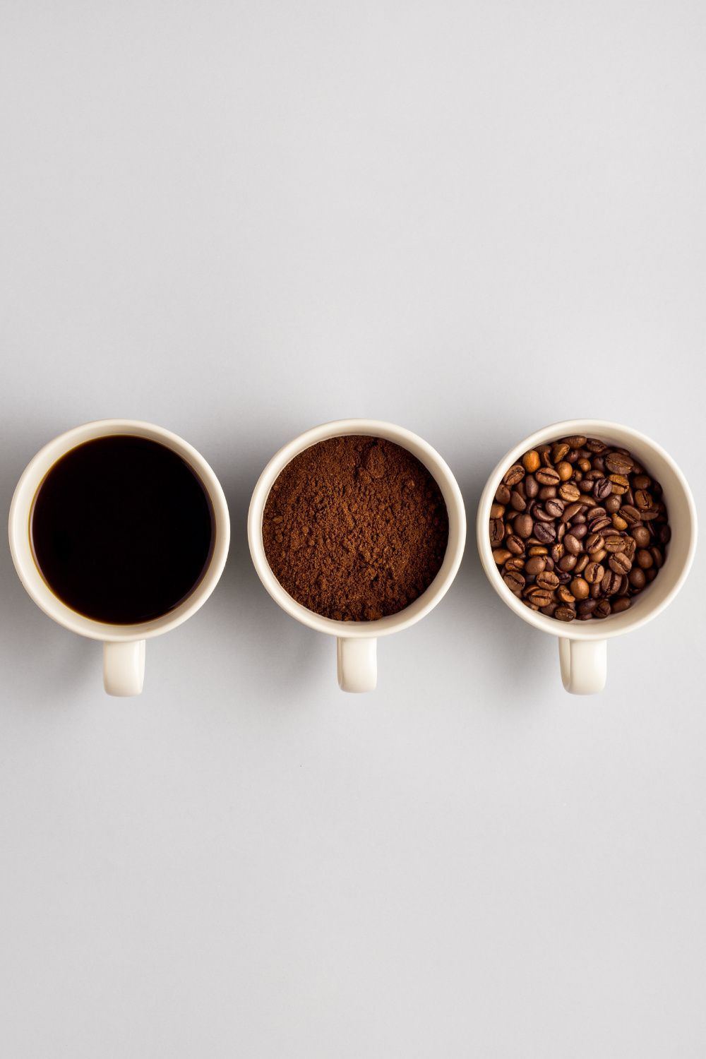 Three cups showing brewed coffee, ground coffee and whole coffee beans