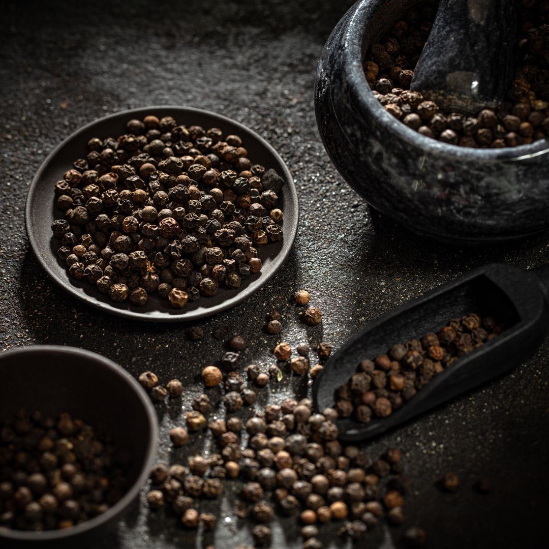 Black peppercorns in a bowl with a mortar and pestle